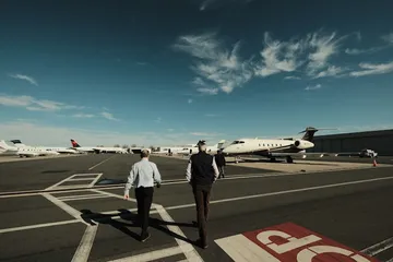 Two travelers walking to their jets on the apron